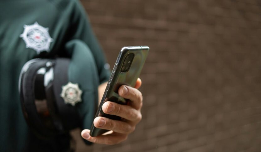 A police officer holding a phone.