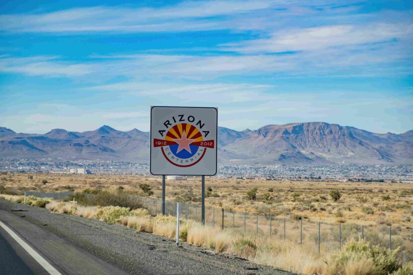 Arizona centennial highway sign overlooking a desert landscape and mountains.
